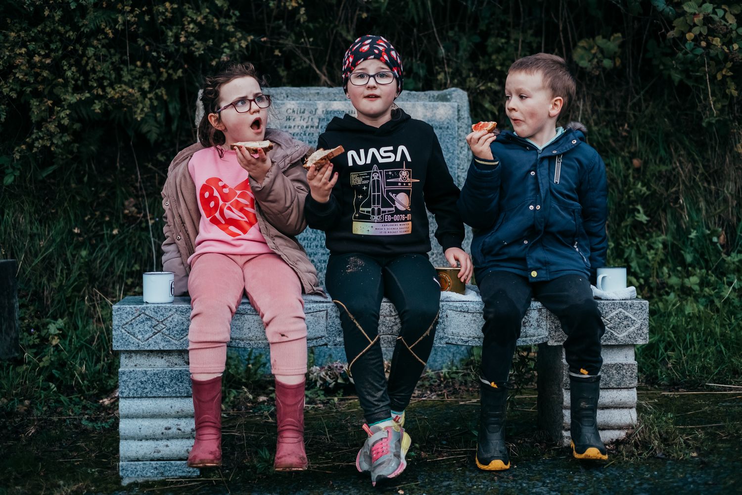 Children and adults sitting together on concrete steps outdoors.