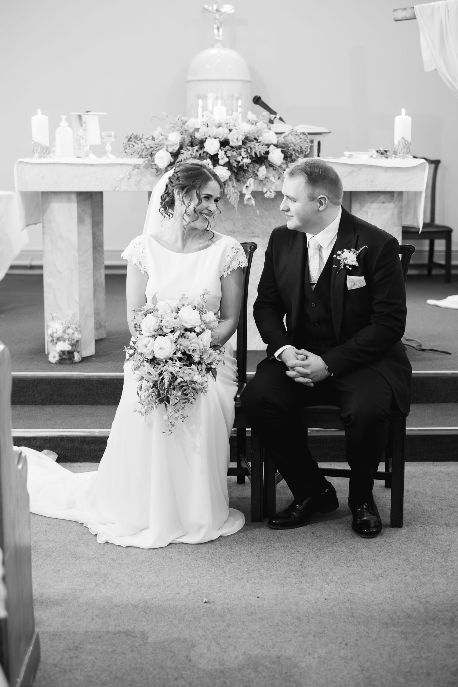 A wedding couple sits on church pews in a series of traditional black and white photographs.