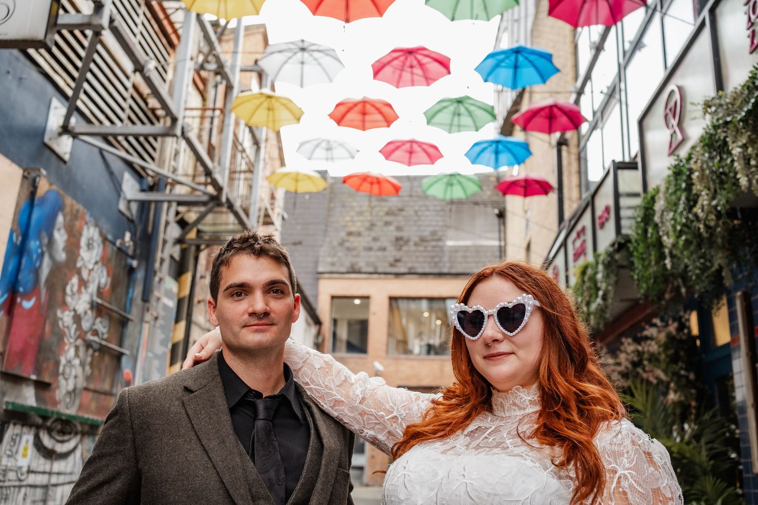 Outdoor alley decorated with colorful suspended umbrellas creating a whimsical atmosphere.