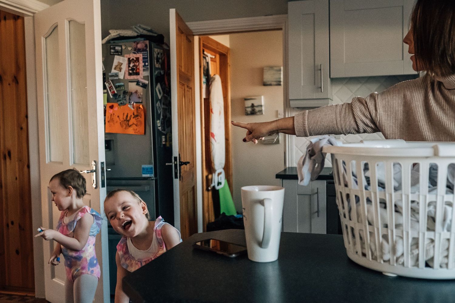 Playful moment in kitchen with laundry basket visible.