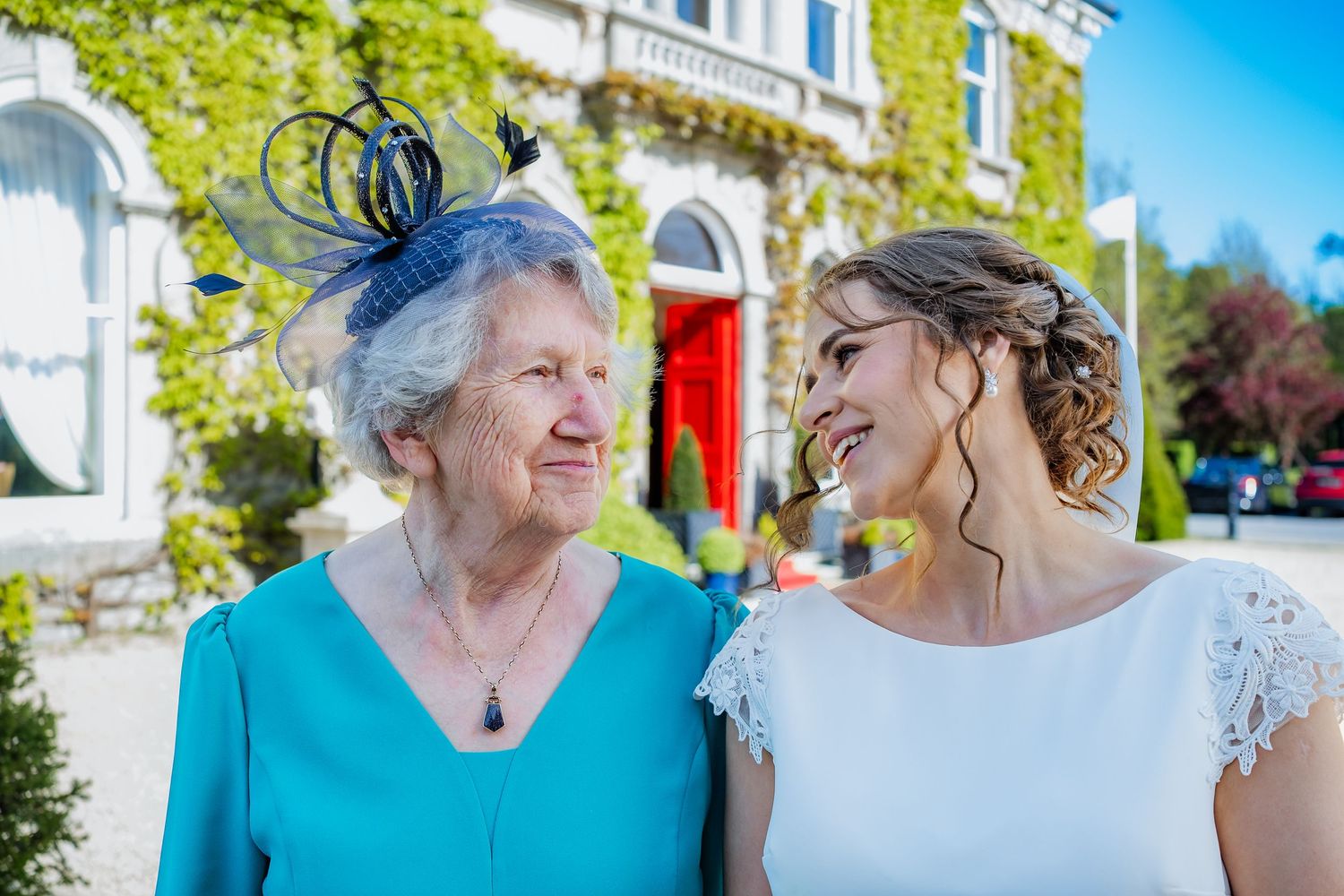 Wedding attendees in bright summer attire gathered outside on a sunny day with blue skies.