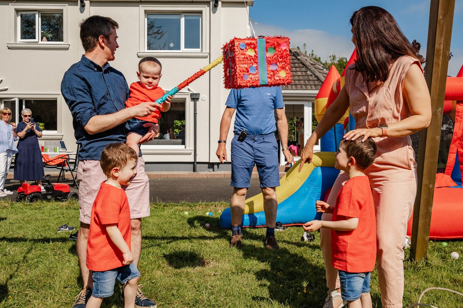 Family gathering in a backyard with playground equipment and colorful clothing.