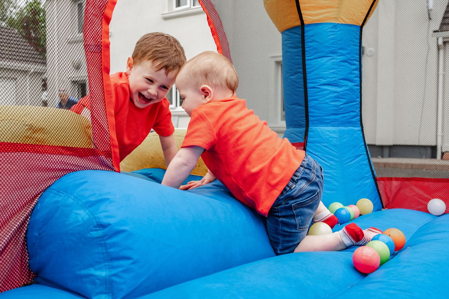 Kids playing together on blue inflatable bouncy castle with colorful balls.