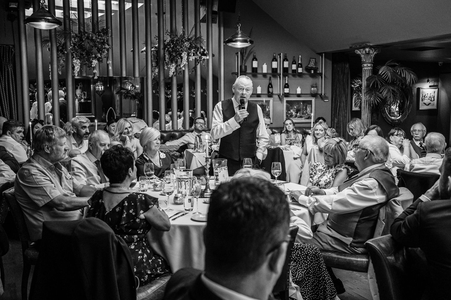 Wedding speech being delivered to attentive guests in a restaurant dining room.