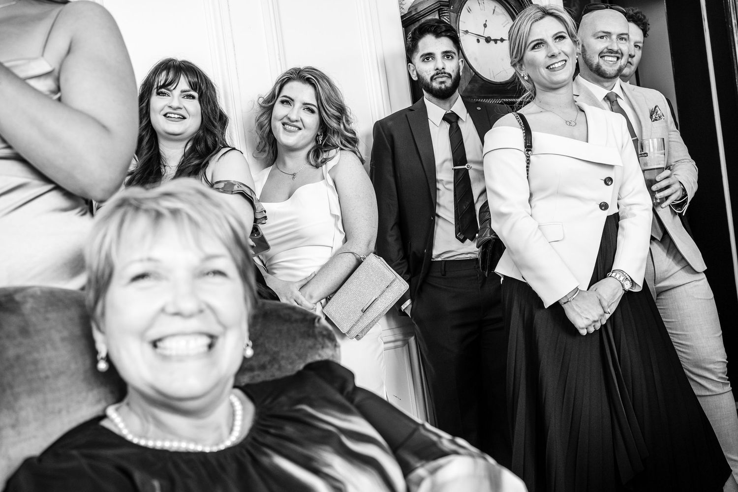 Black and white candid shots of wedding guests laughing and interacting during reception.