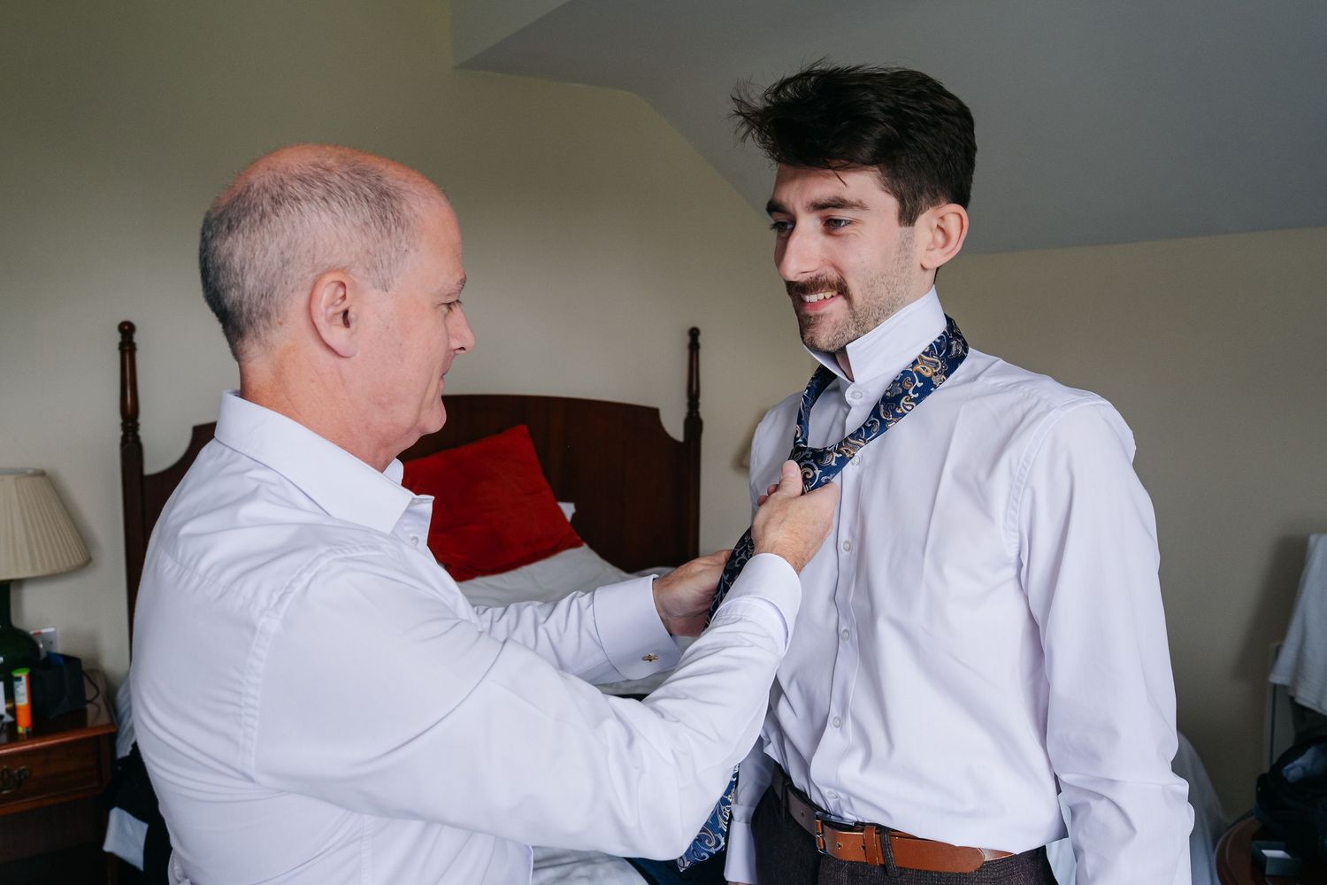 Morning wedding preparations show formal attire adjustments in a sunlit room.