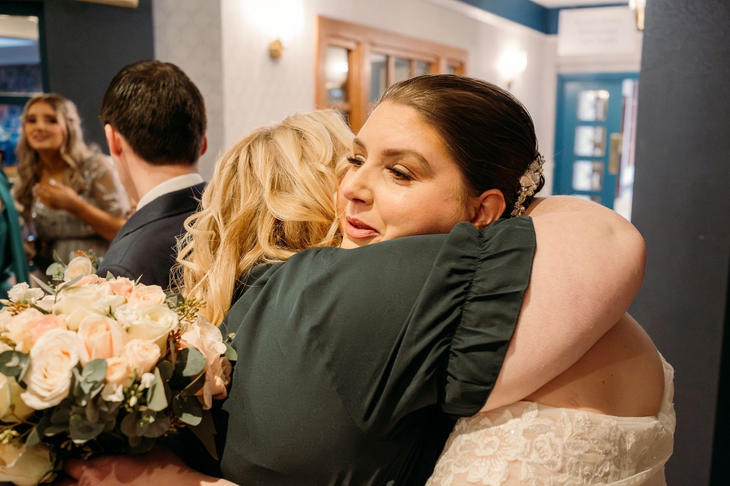 An emotional embrace shared during wedding celebrations in a hallway.