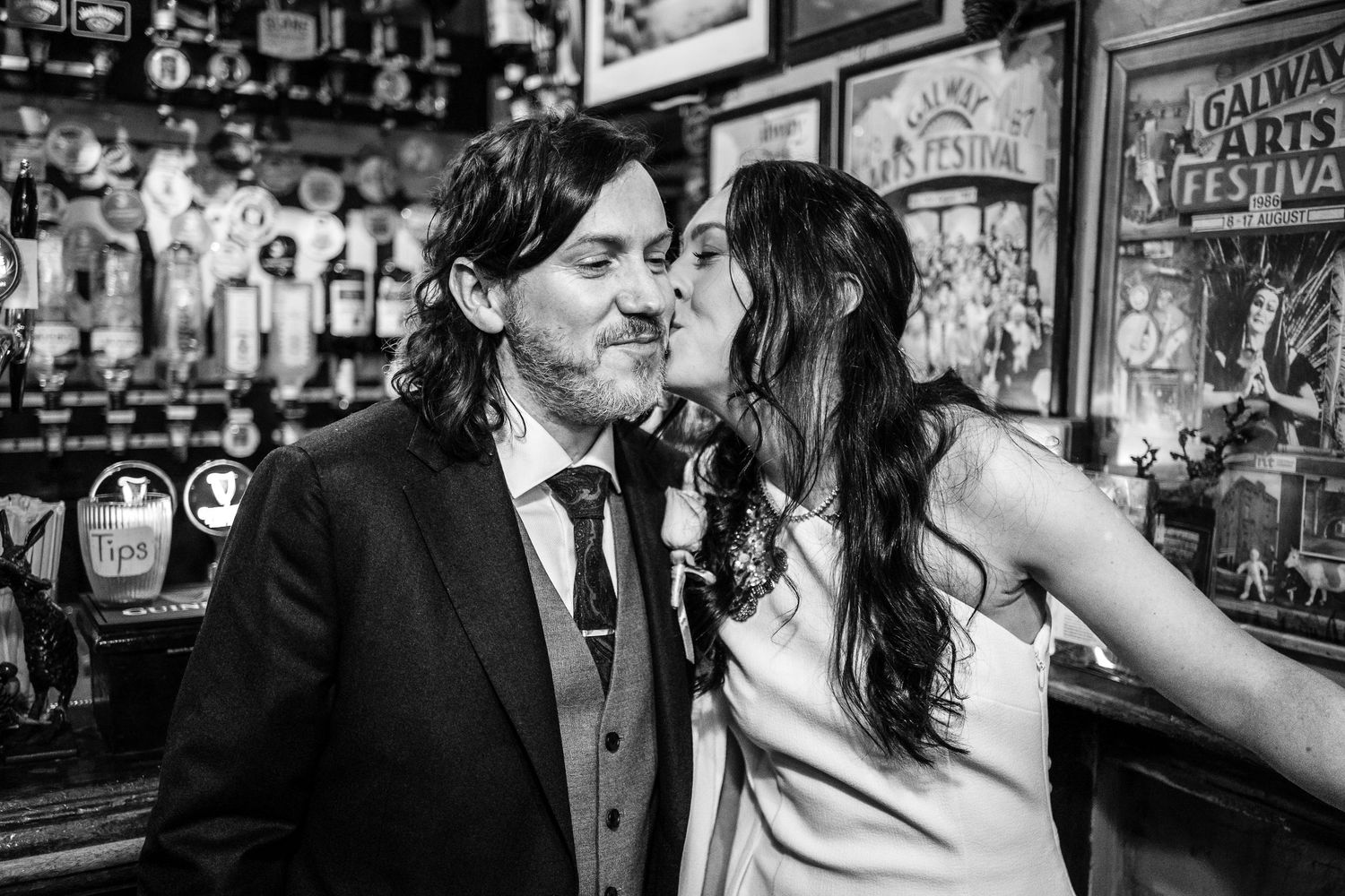 Couple sharing a kiss at a bar in a black and white wedding photo.