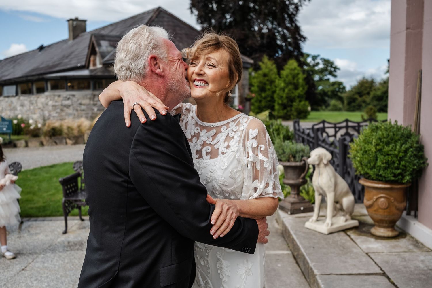 A joyful moment shared between two people on an outdoor patio with a statue.