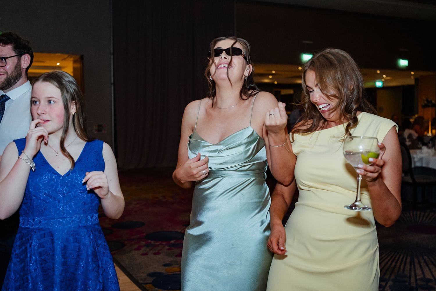 People in pastel dresses dance and socialize during an evening reception event.