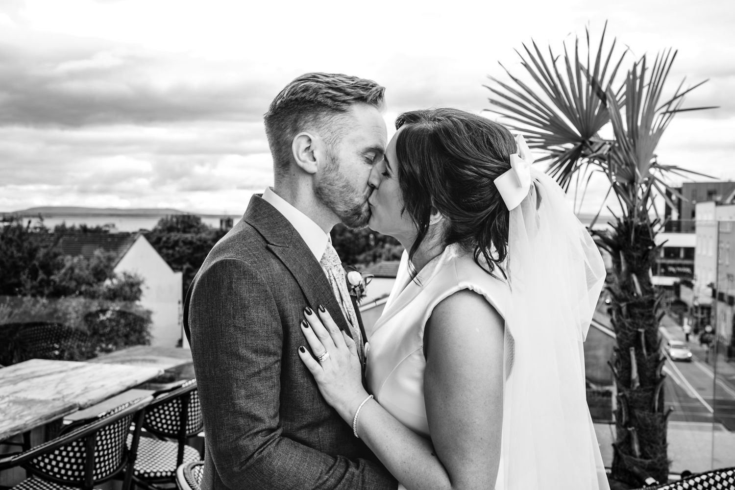 Romantic black and white wedding portrait with palm tree in background.