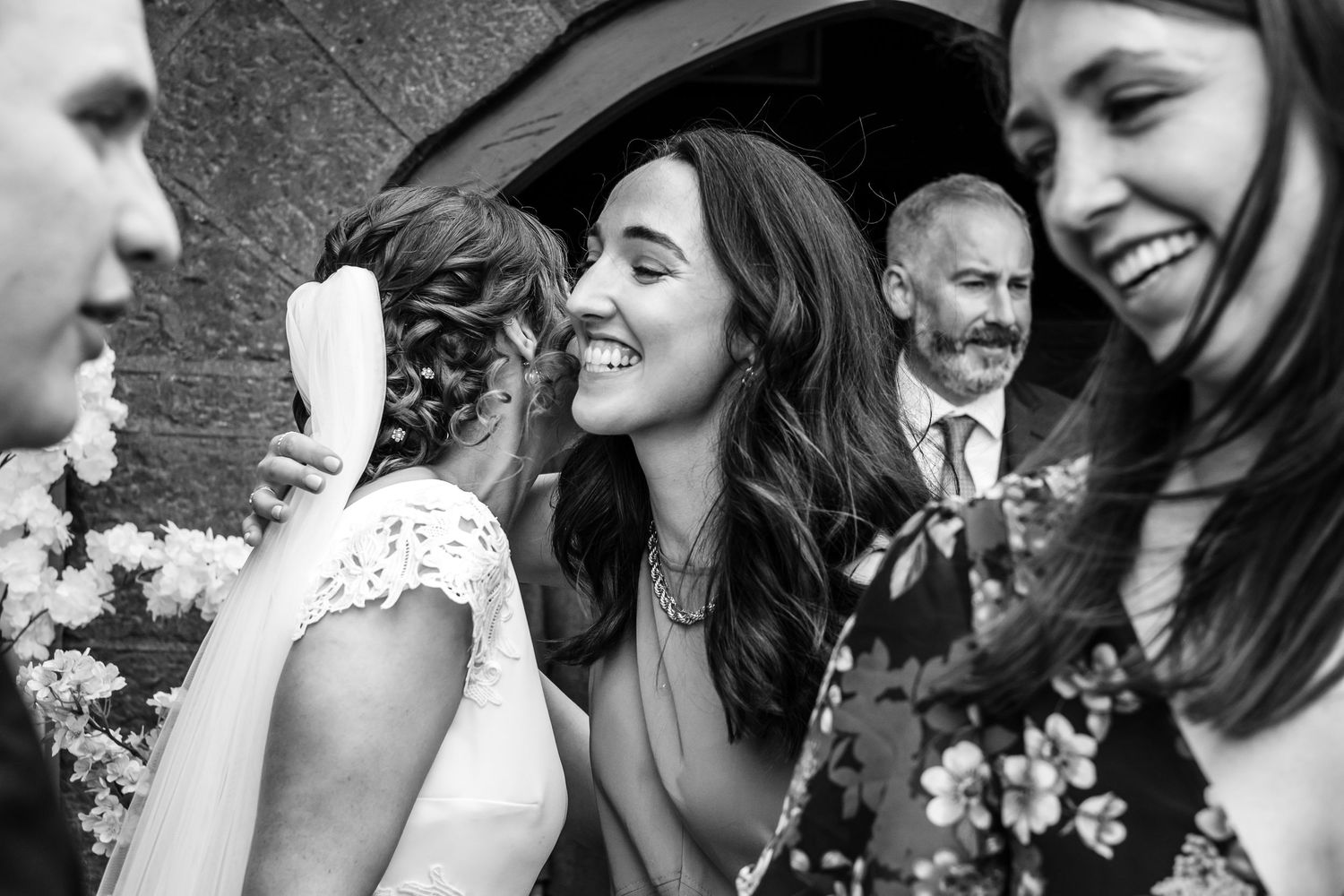 Candid black and white photo showing laughter and smiles among wedding attendees.