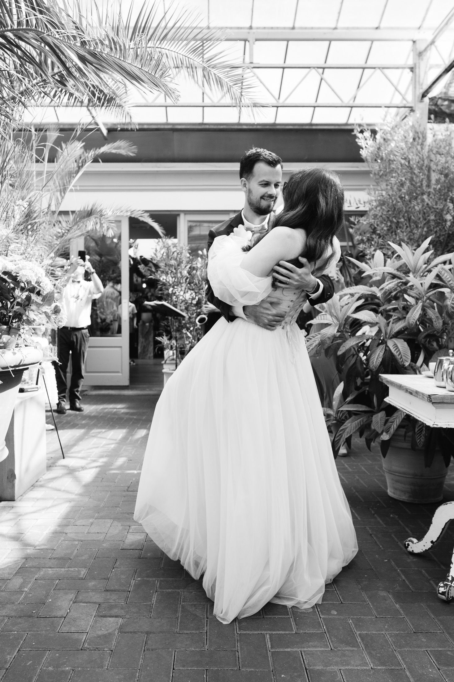 Black and white photo of a bride and groom sharing their first dance at an outdoor wedding reception.