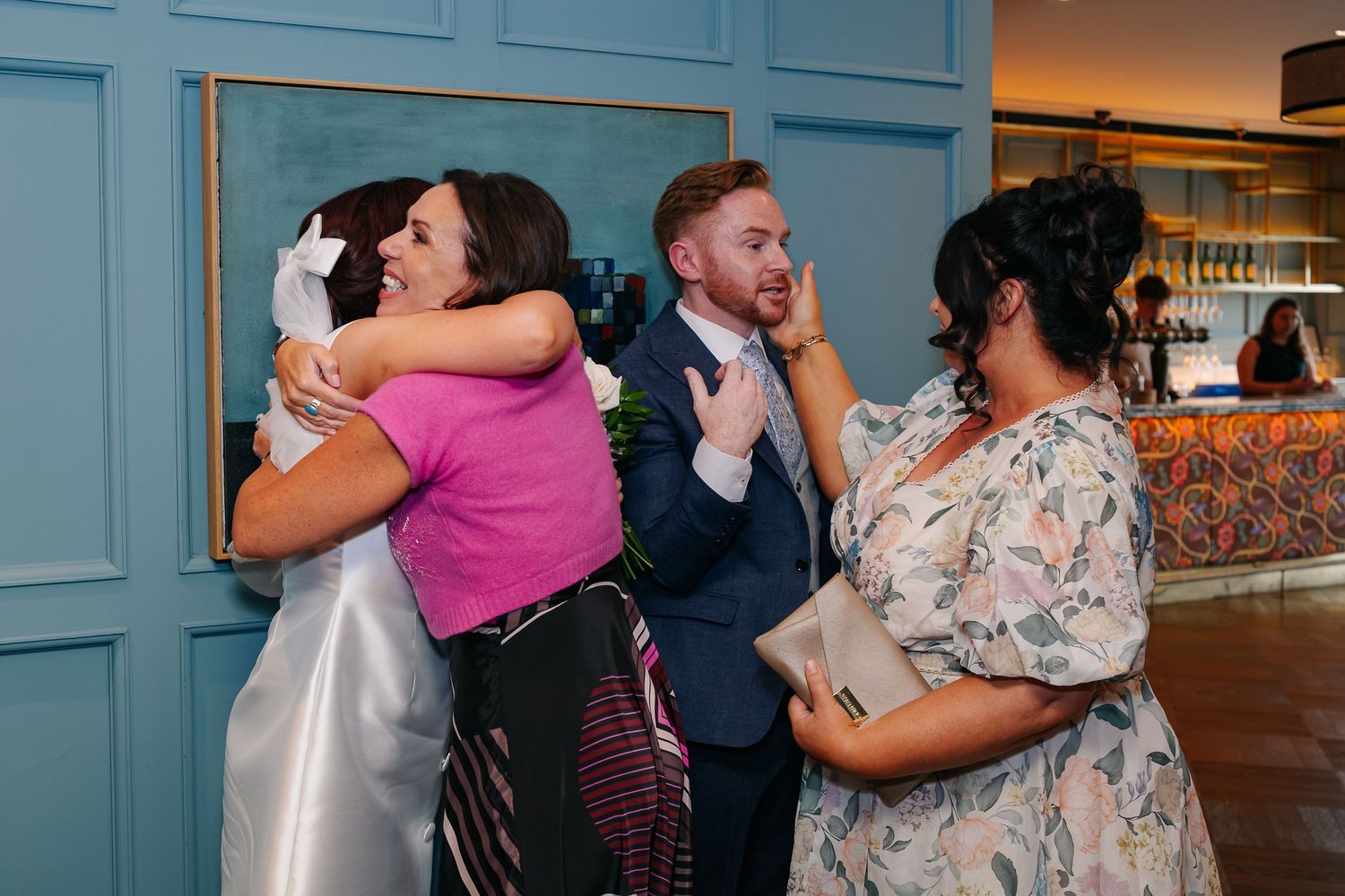 Wedding party dancing and celebrating in a venue with bright blue walls.