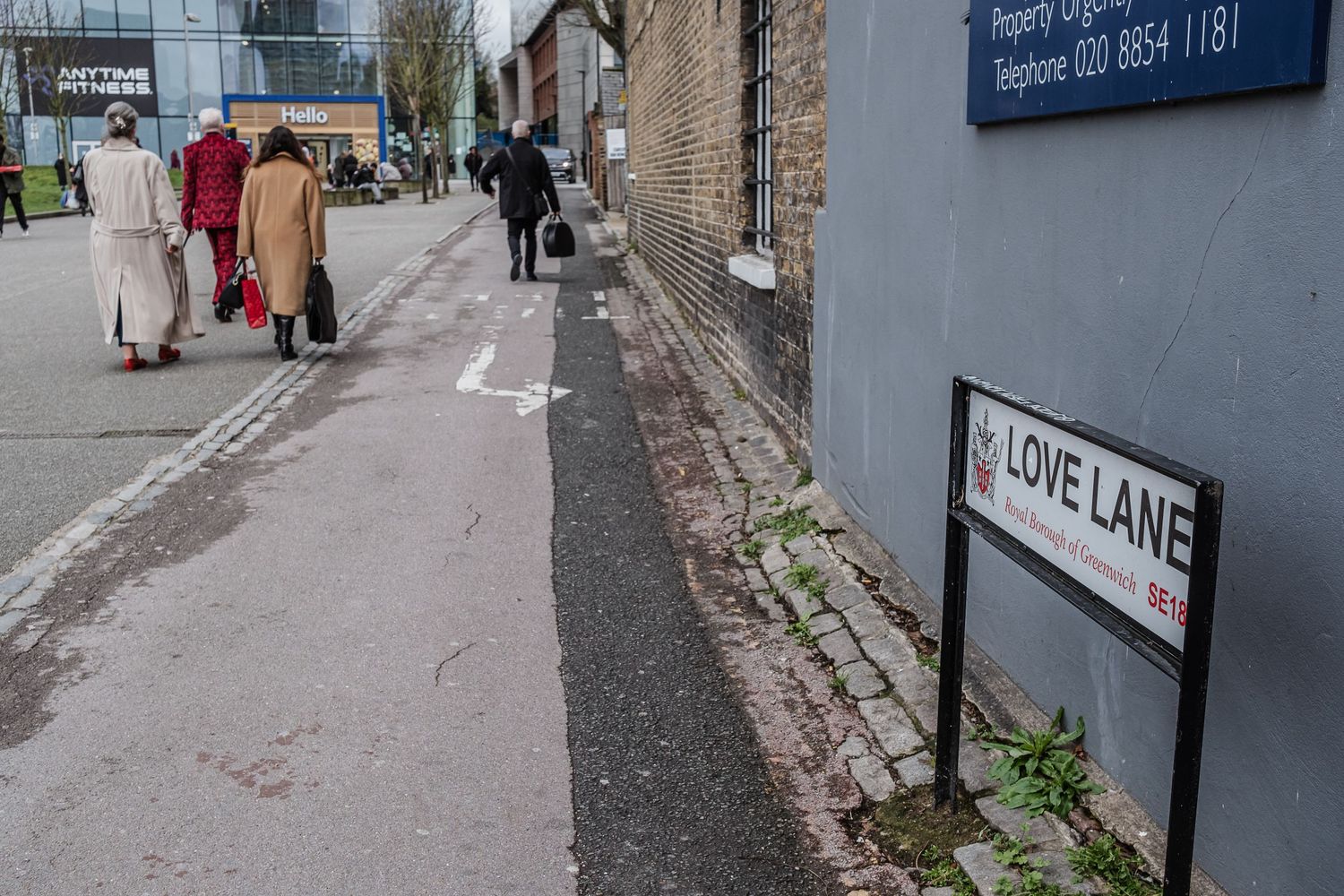People walking down urban street with 'Love Lane' street sign visible in foreground.