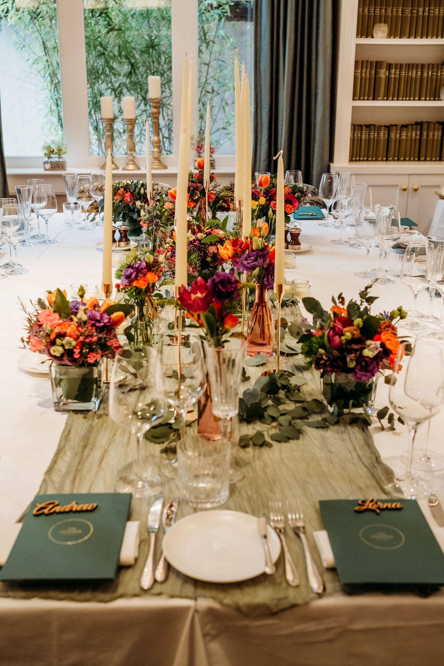 Elegant wedding tablescape with colorful floral centerpieces and tall white candles.