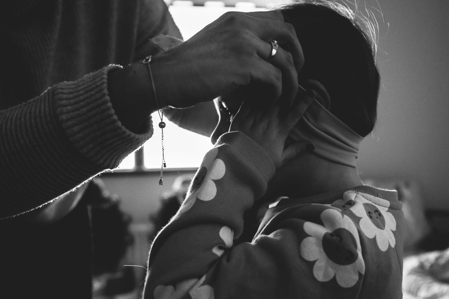 Black and white image of someone in a polka dot outfit adjusting their face.