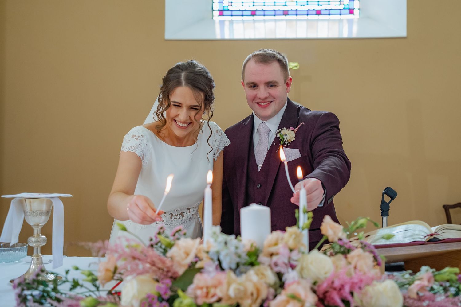 Wedding party seated at an elegant head table decorated with floral centerpieces.