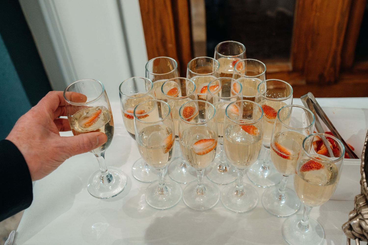 Champagne flutes garnished with orange slices are arranged on a white tablecloth.