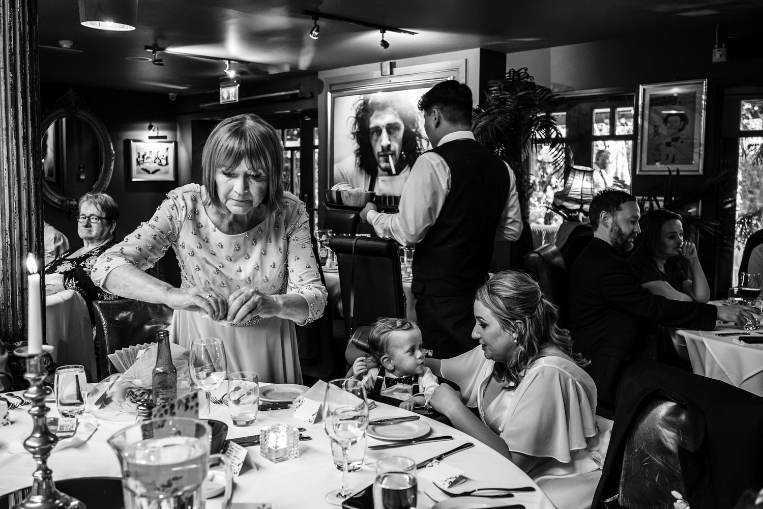 Black and white photo of wedding guests dining in an intimate restaurant setting.