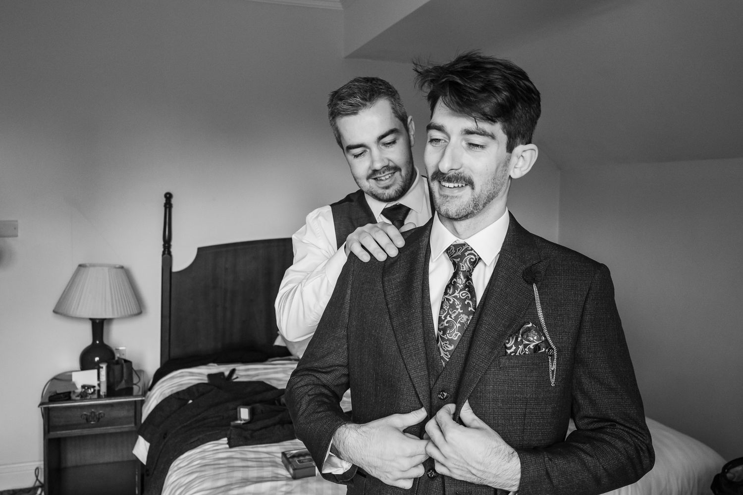 Two people in formal attire sharing a candid moment while getting ready.