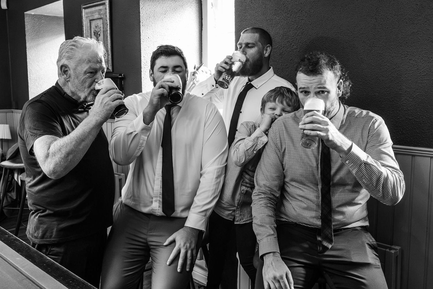 A group of men in formal attire share drinks together at a venue.
