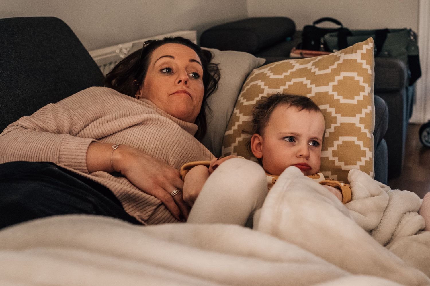 Relaxing together under blankets on a couch with decorative pillows.