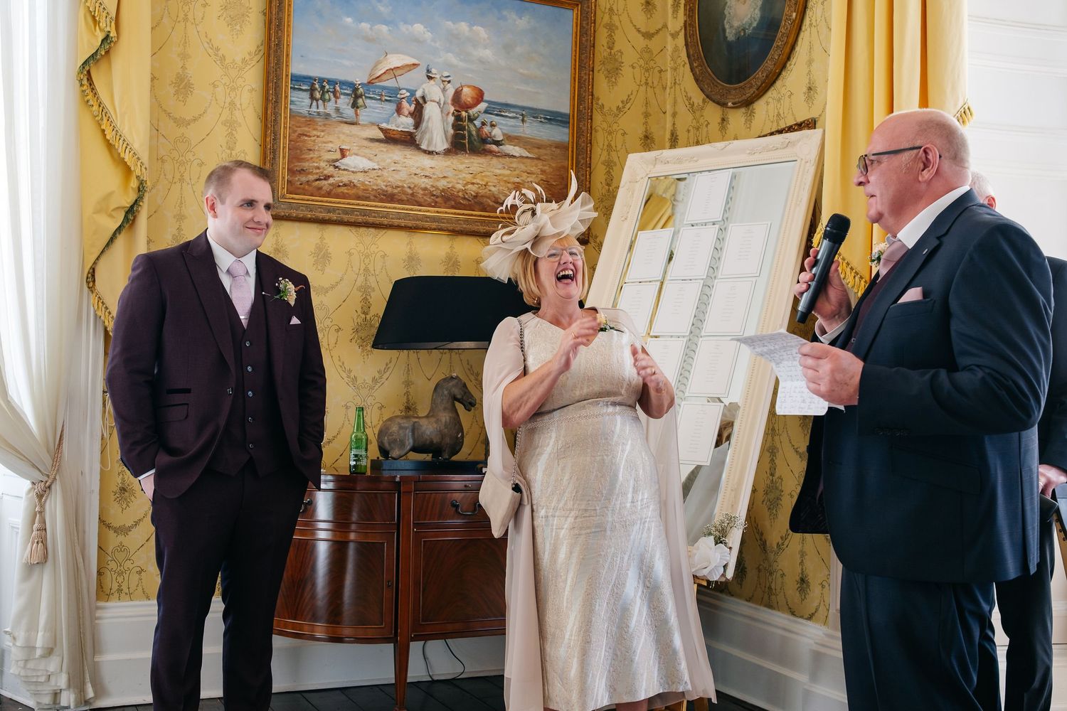 Wedding party members singing from songbooks during a traditional ceremony in an elegantly decorated room.