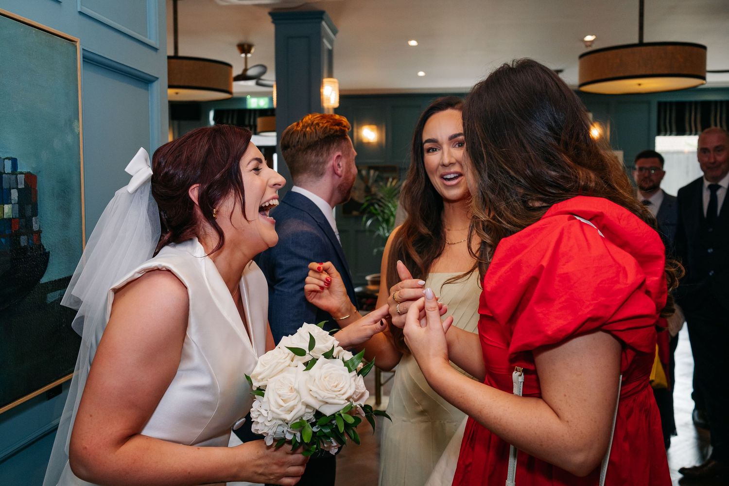 Multiple wedding party members sharing emotional moments and embracing during a reception celebration.