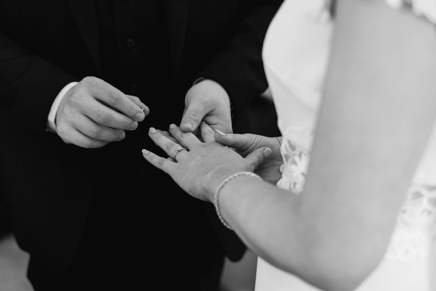 Close up photos of hands exchanging wedding rings during a marriage ceremony.