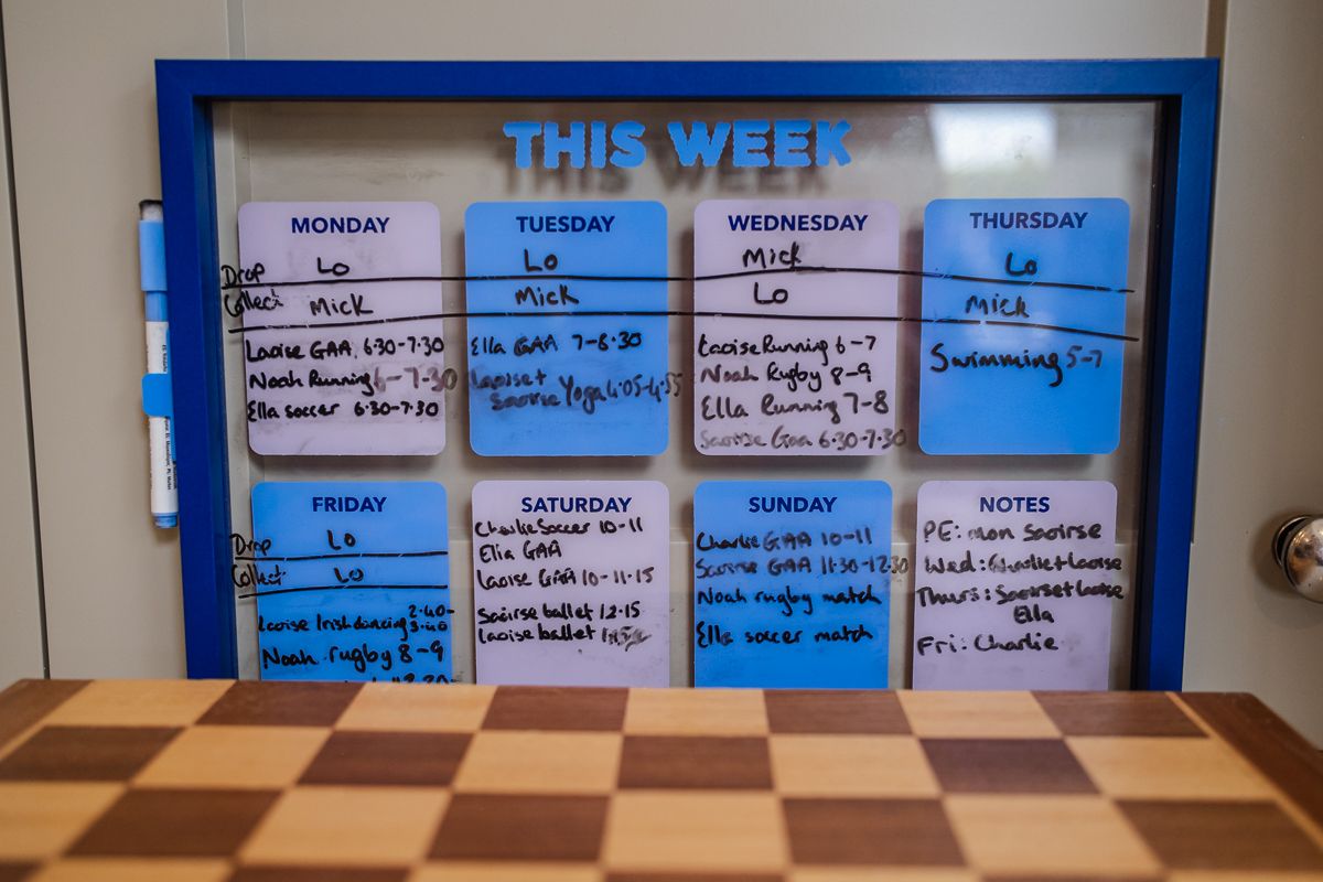 A weekly family schedule whiteboard with colorful sticky notes organizing activities and tasks for each day of the week.