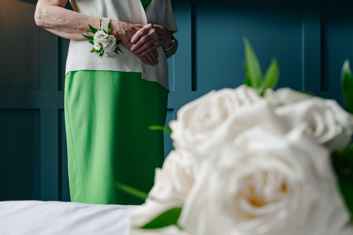Close-up detail of white roses and floral arrangements against a dark blue wall background.