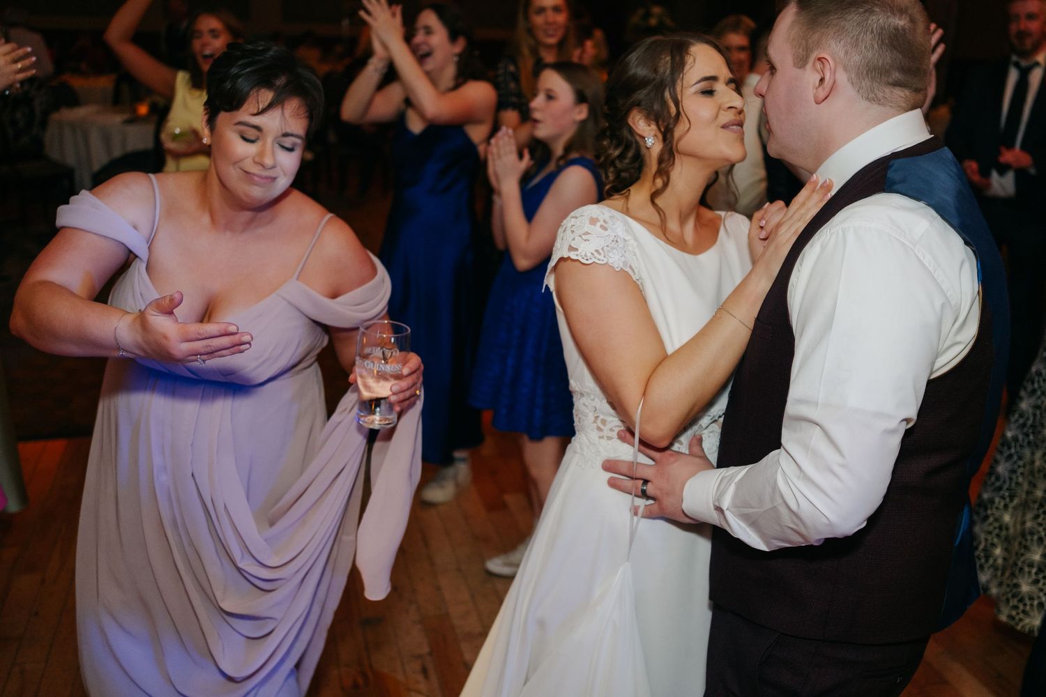 Dancing guests enjoy themselves on a dance floor at a wedding reception party.