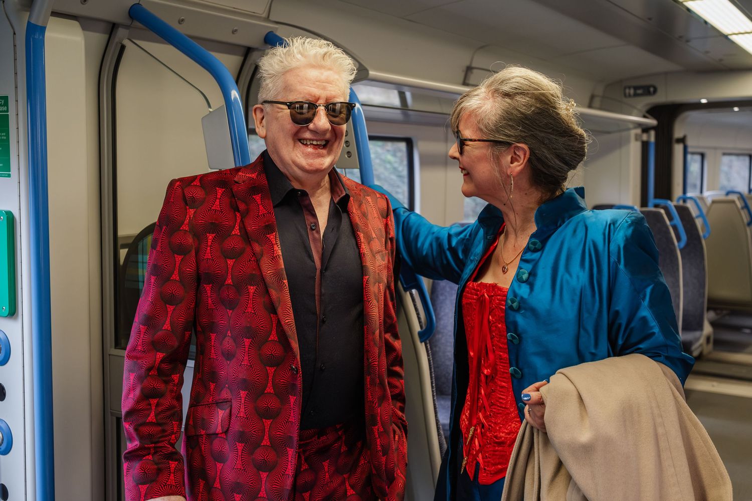 Two people sharing a moment in bright contrasting outfits on public transport.