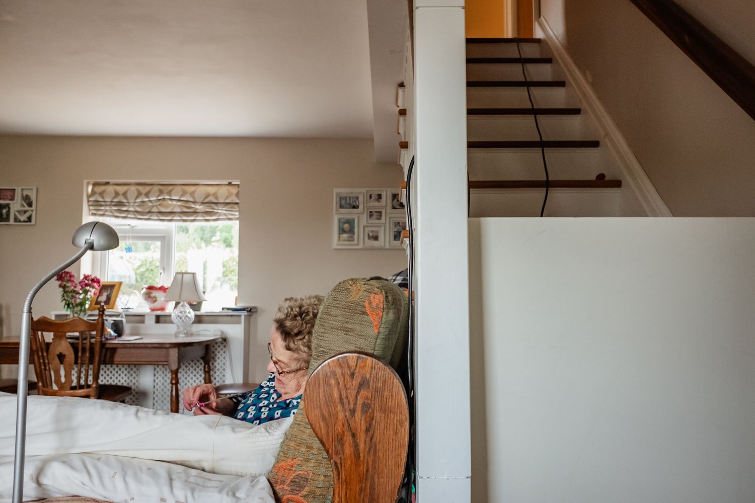 A cozy living room interior with wooden stairs and window light.