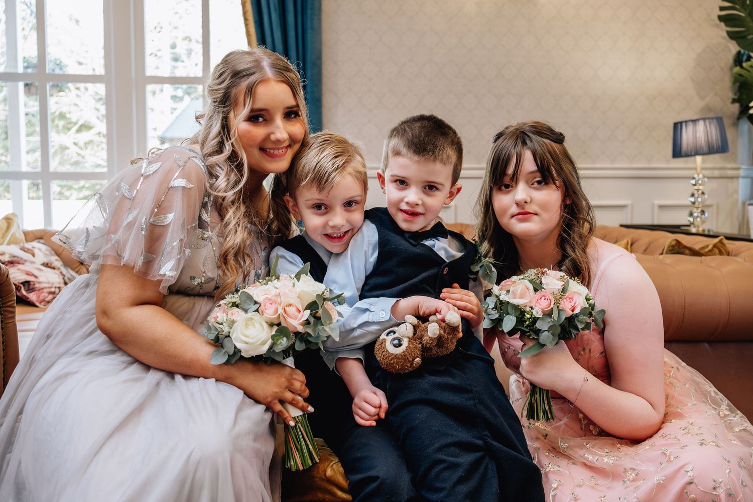 Wedding party group portrait with flowers on elegant sofa.