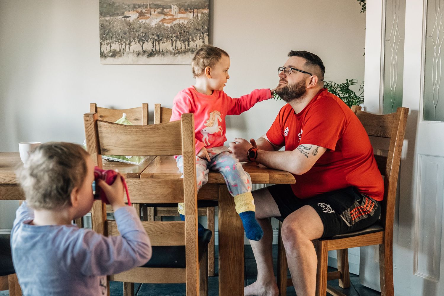 Family taking pictures together during a casual mealtime at home.