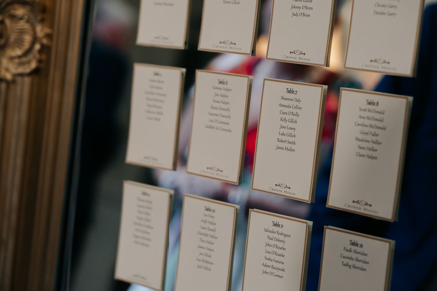 Wedding seating chart cards displayed on a mirror, showing table assignments for guests at an elegant reception venue.