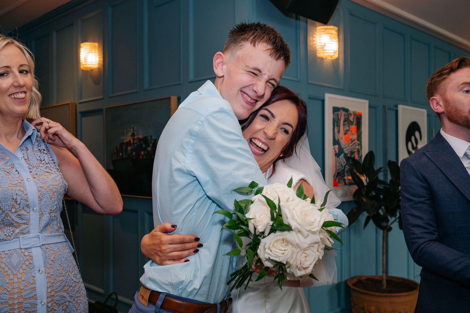 Emotional wedding ceremony moments captured in a venue with blue wall panels.
