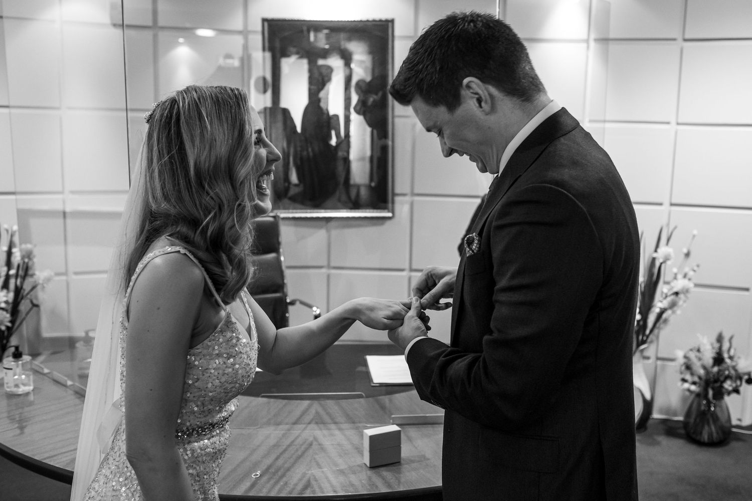 A black and white candid moment between a couple exchanging rings or vows.