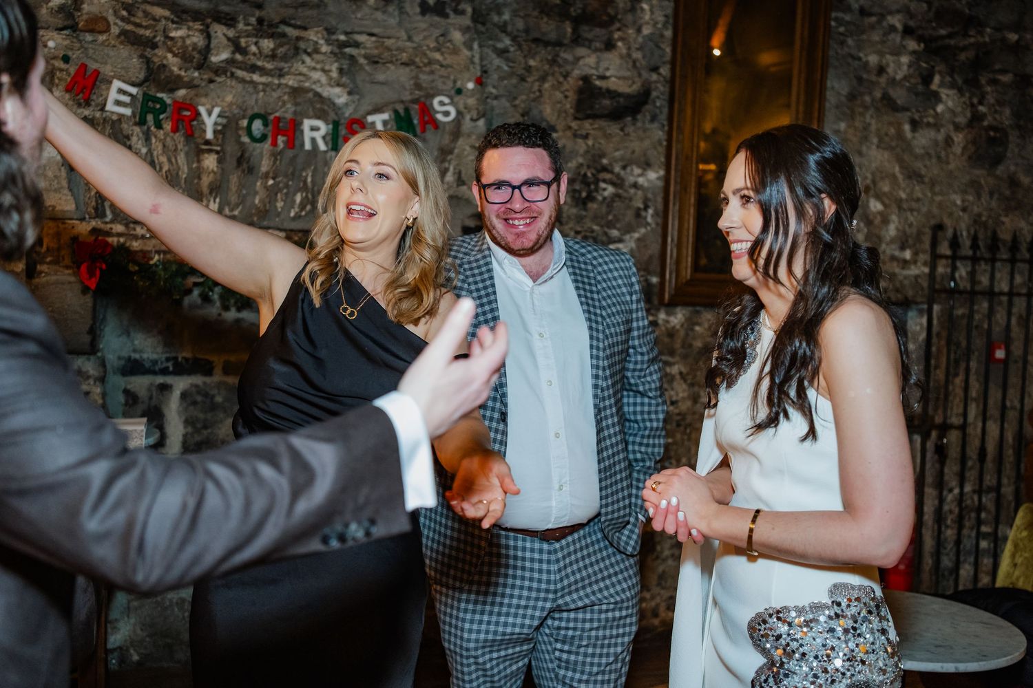 People laughing and celebrating at a Christmas party in a rustic venue with festive bunting.