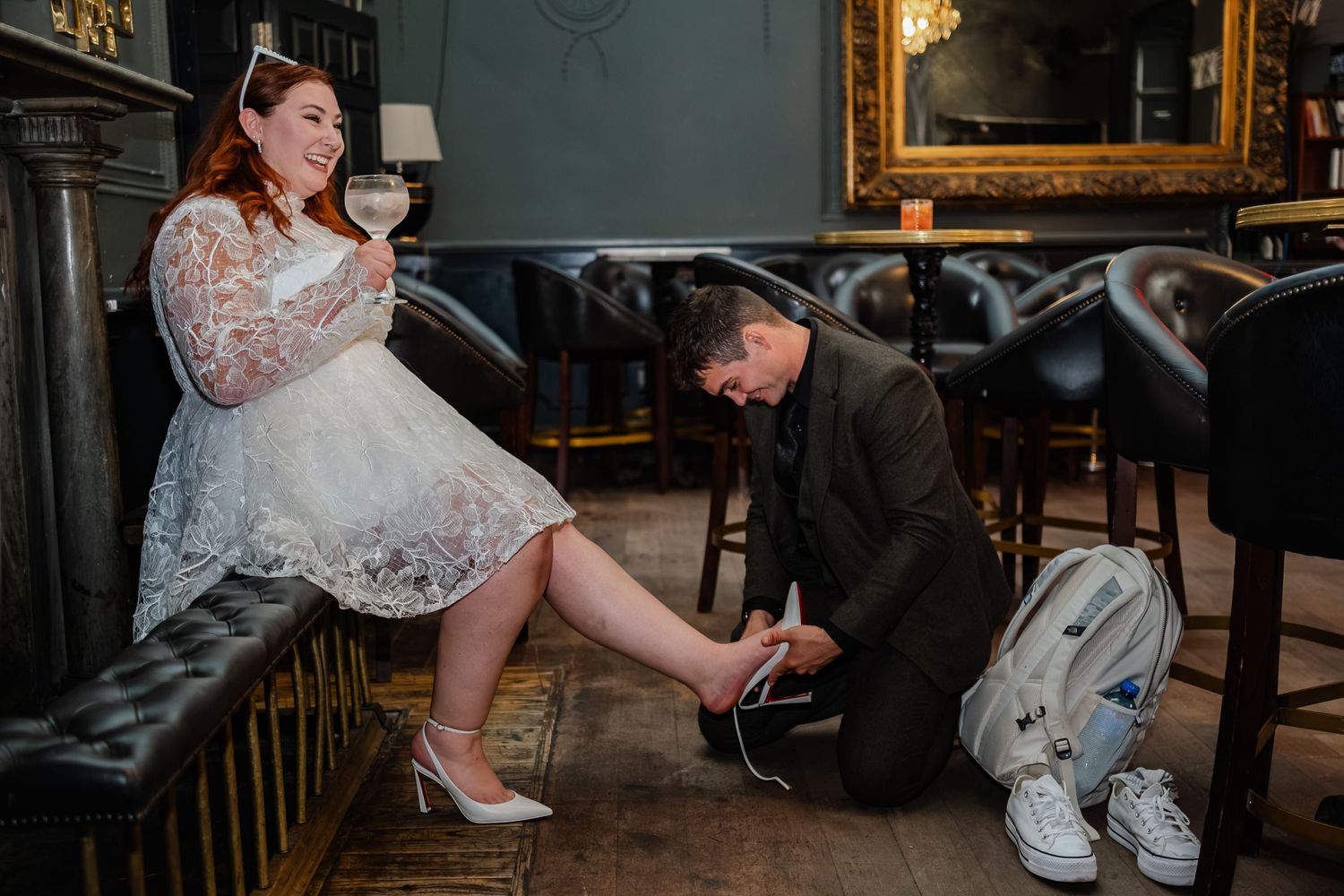 Romantic scene in a vintage bar interior with a white lace dress and shoe tying moment.