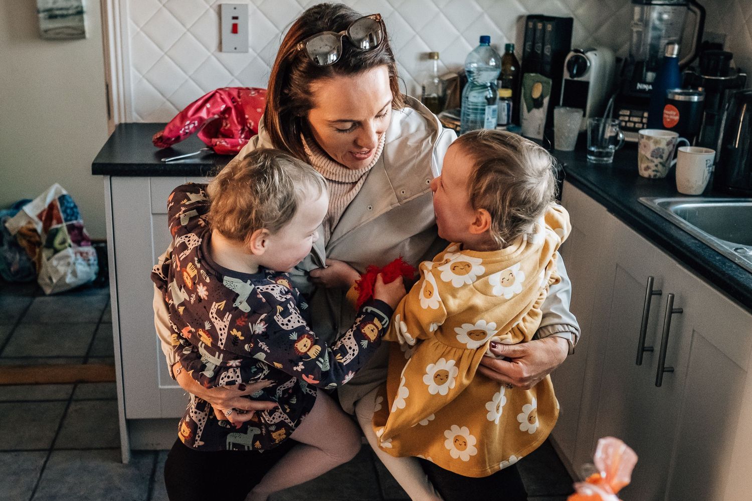 A heartwarming moment shared in a modern kitchen between family members wearing patterned clothing.