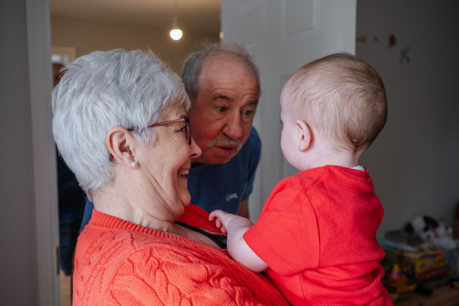 Candid family moment showing playful interaction with a young child in red clothing.
