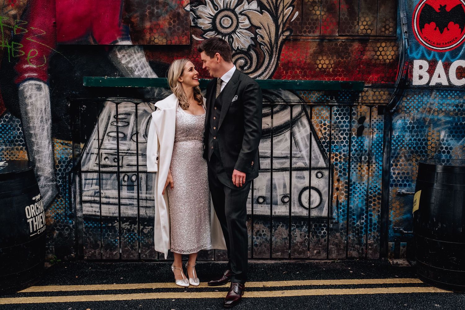 Couple sharing an intimate moment against colorful street art background.