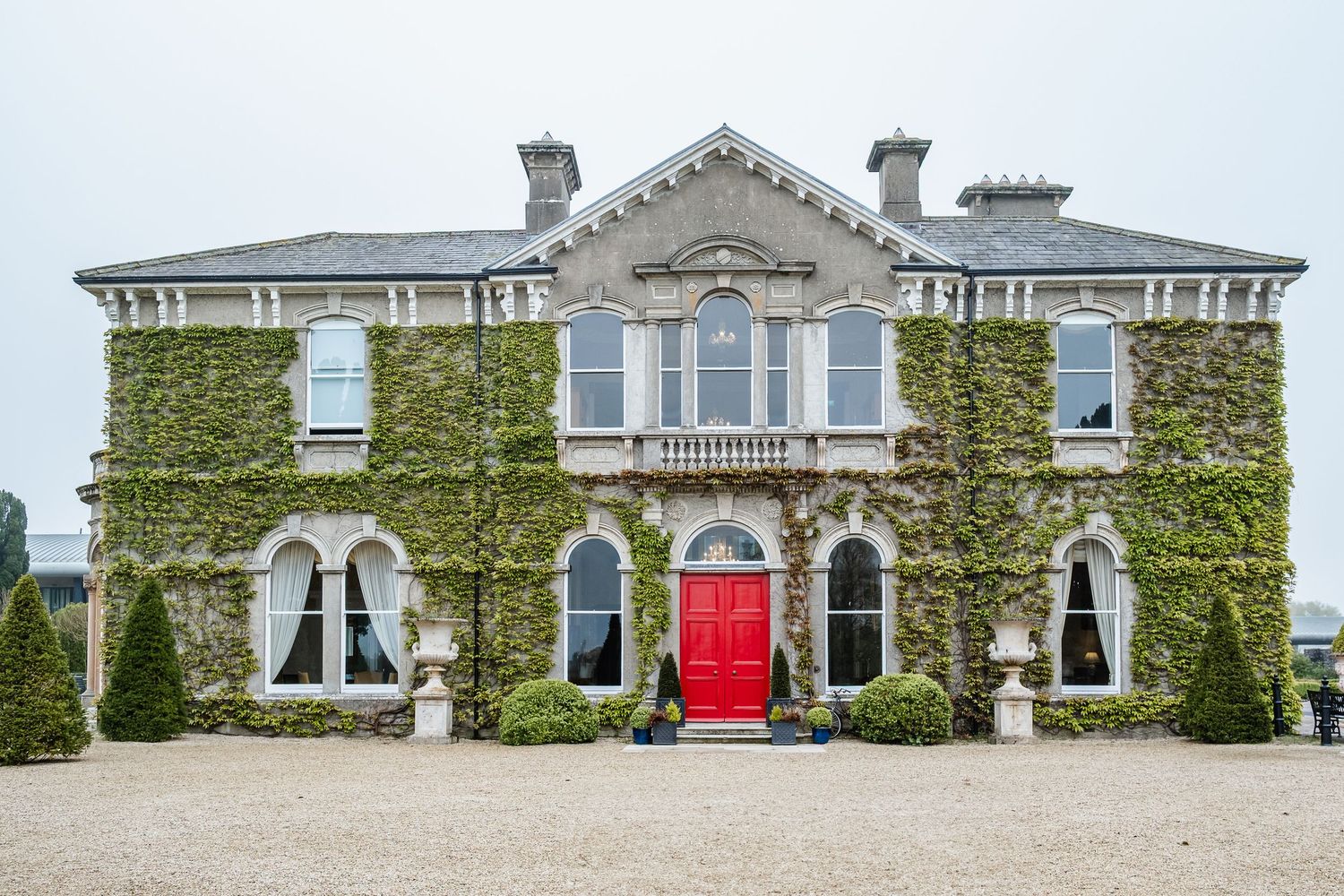 Historic ivy-covered stone mansion with white trim and arched windows extends across the landscape.