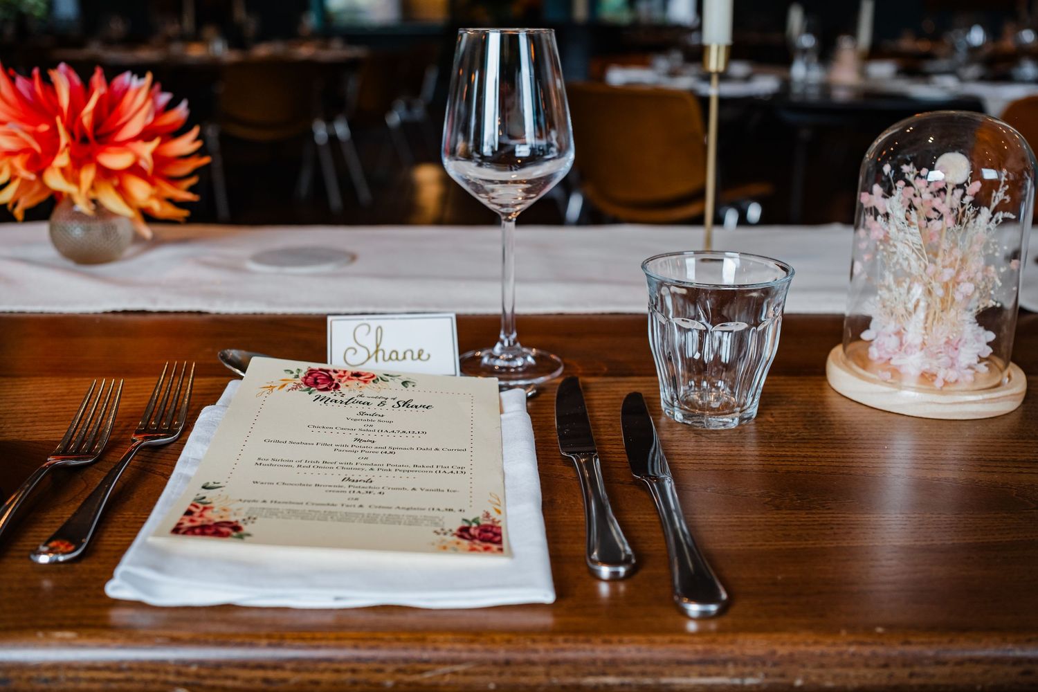 Elegant table setting with menu card, wine glass, and floral decor at a fine dining restaurant.