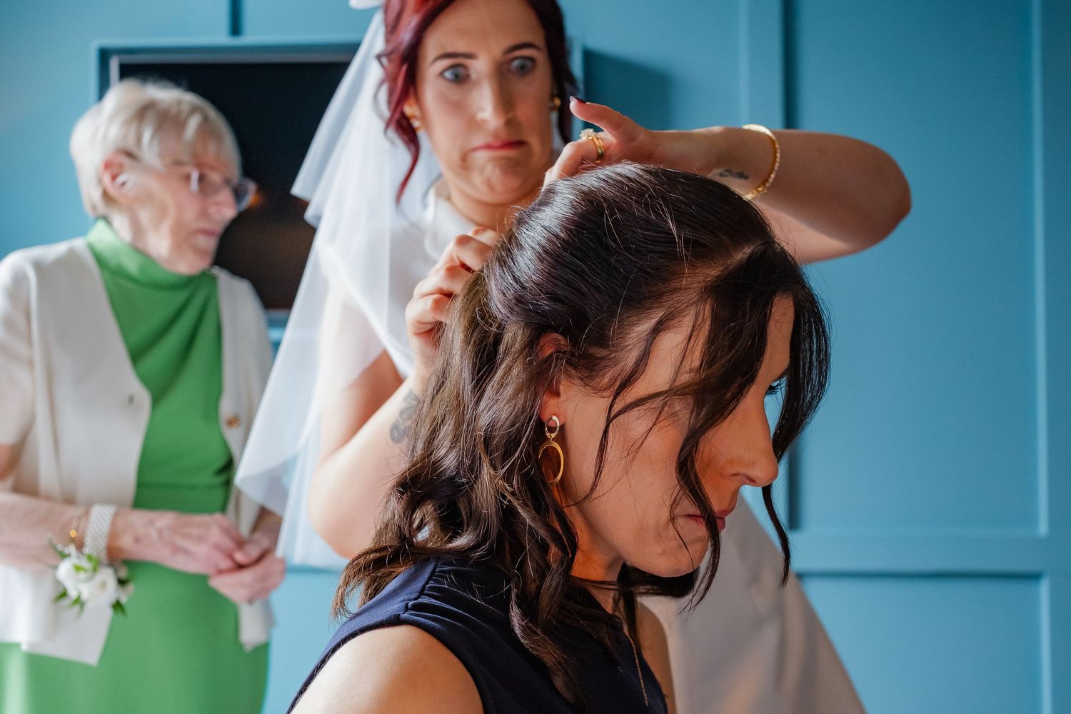 Wedding guests celebrate on a dance floor in a room with blue walls and warm lighting.