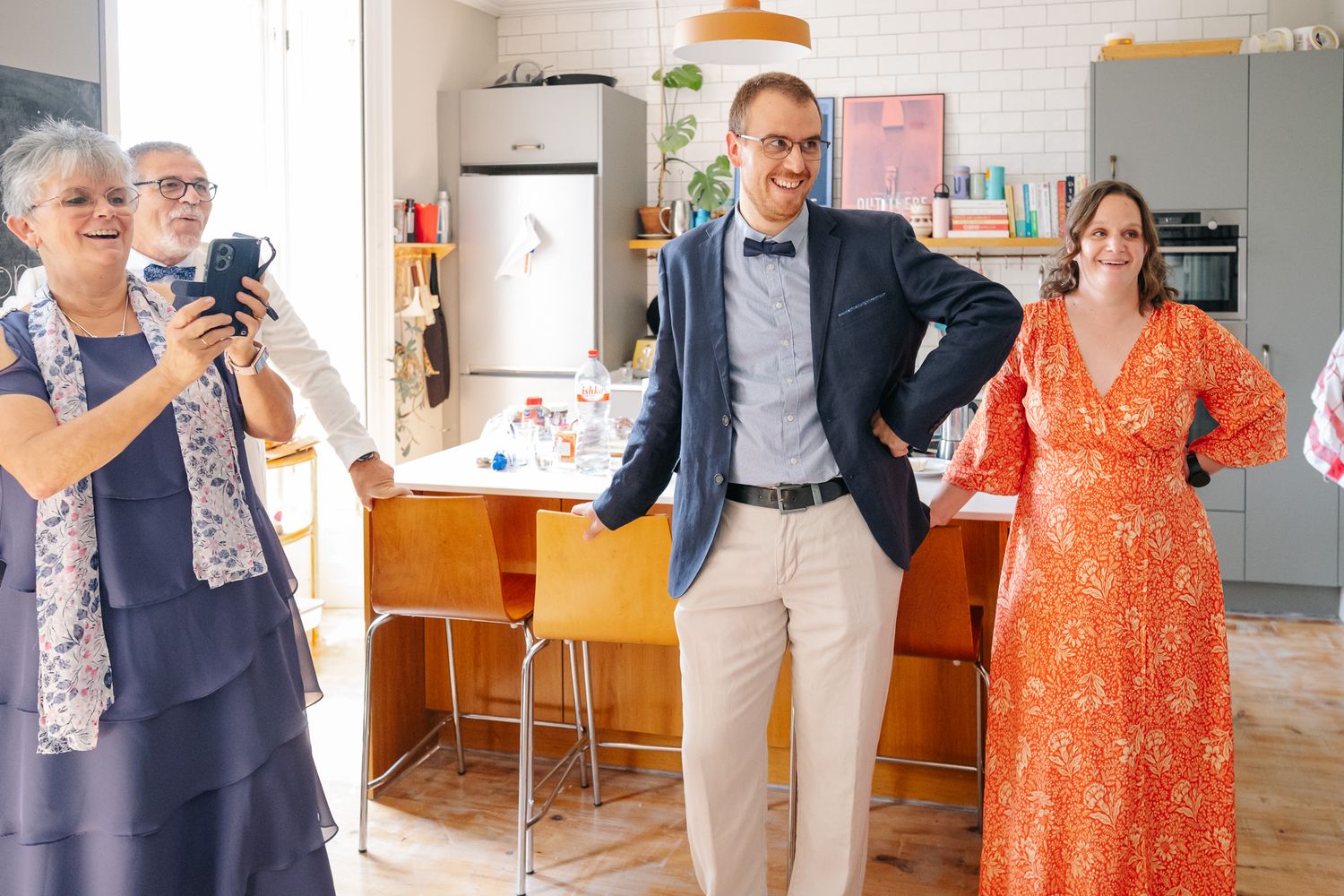 Joyful family gathering in a modern kitchen, with guests in elegant attire celebrating a special occasion.