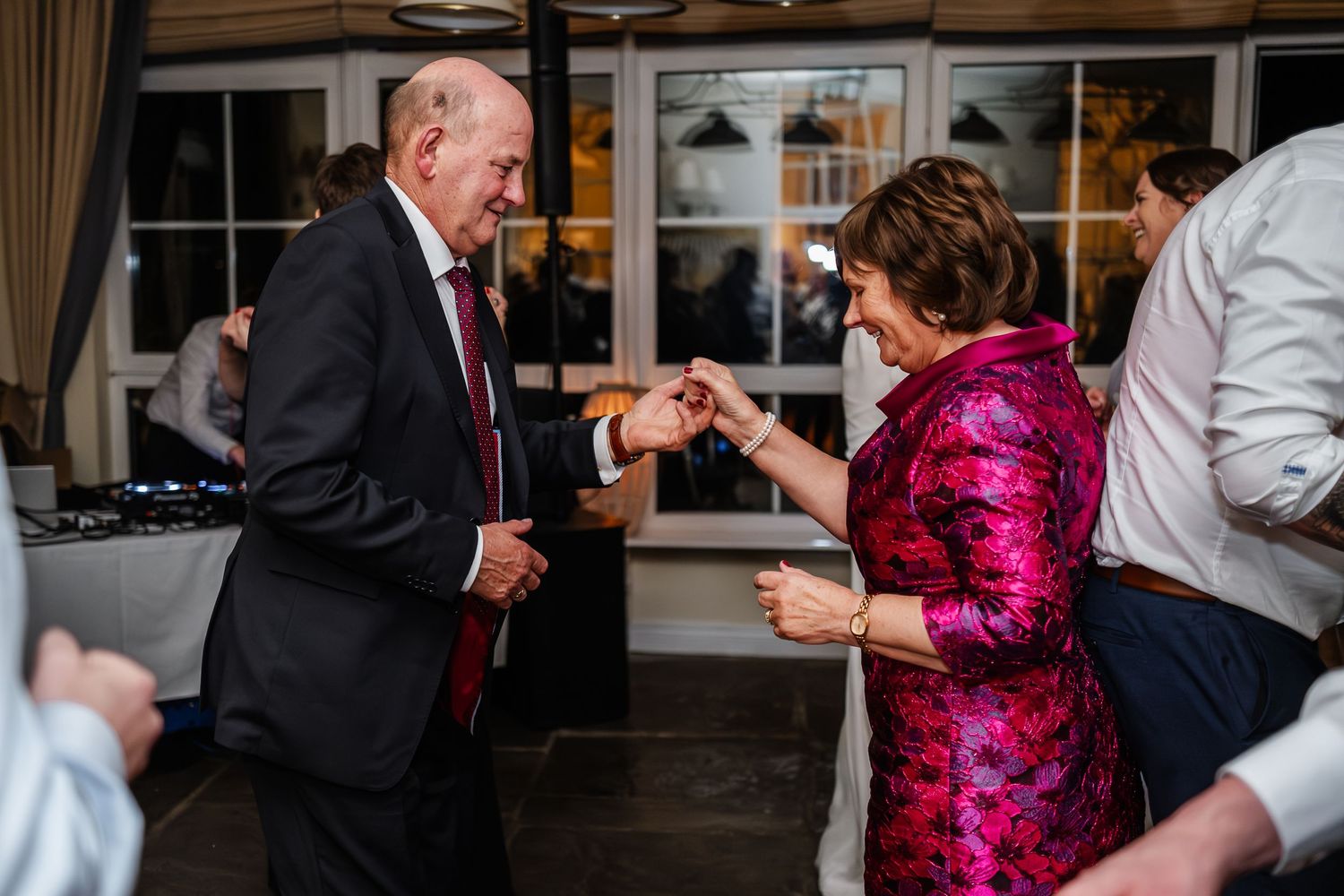 Elderly couple sharing a romantic dance together at a wedding reception in a warmly lit venue.